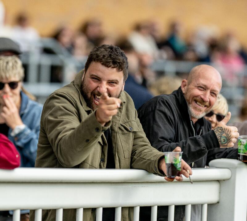 A race goer smiles and points at the camera at Fontwell