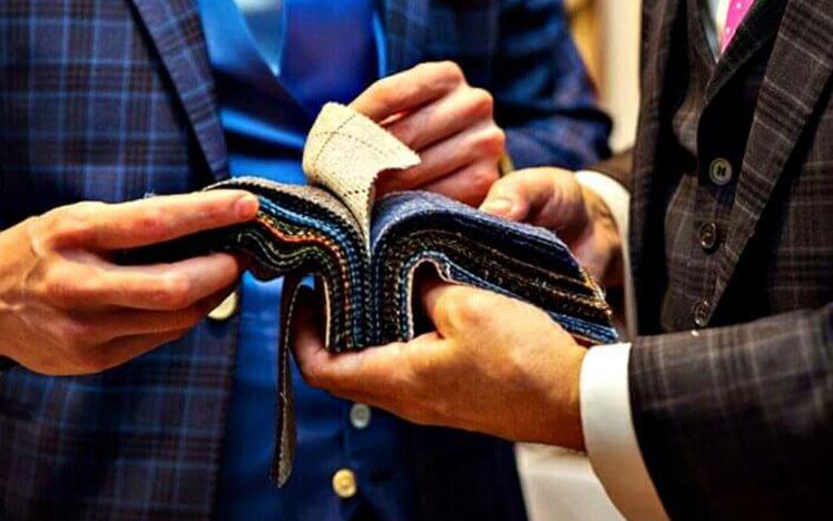 Two gentlemen looking through a cloth samples.