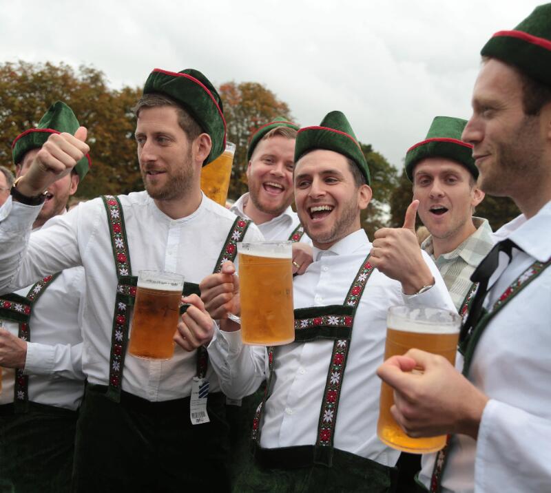 A group of guys dressed up for Oktoberfest enjoying their beers.