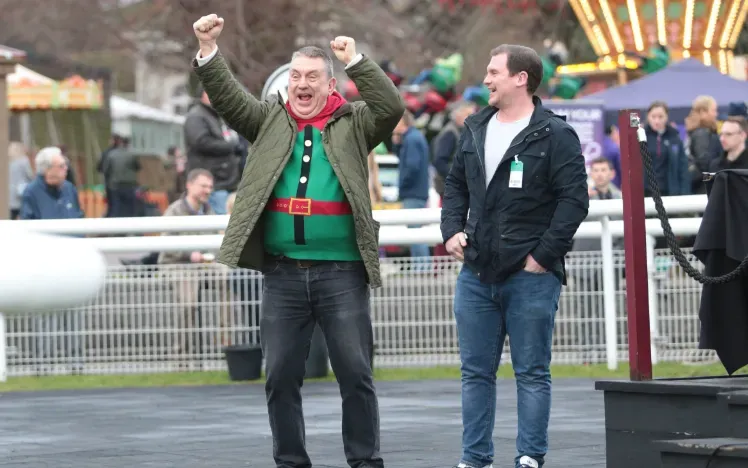 A race goer in a Christmas jumper cheers at Fontwell Park