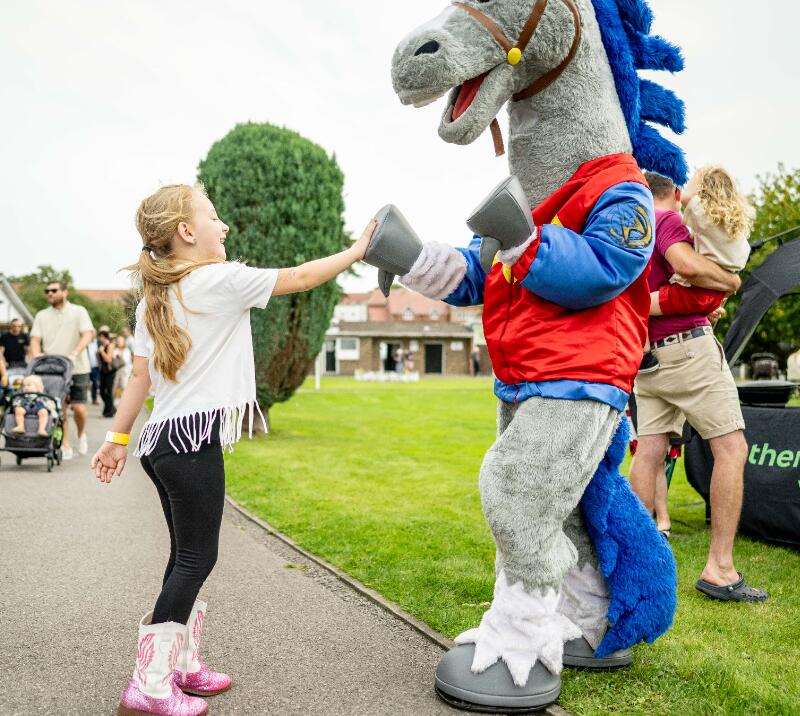 A child high fiving the horse mascot at Fontwell Park