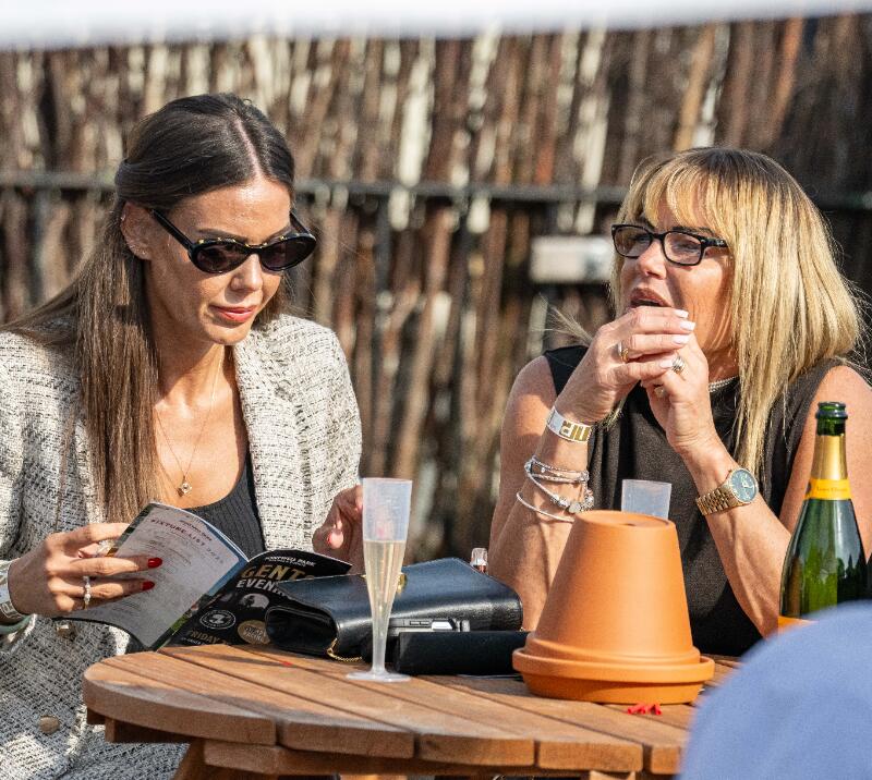 Two ladies sit at a table at Fontwell Races, one reading the race card