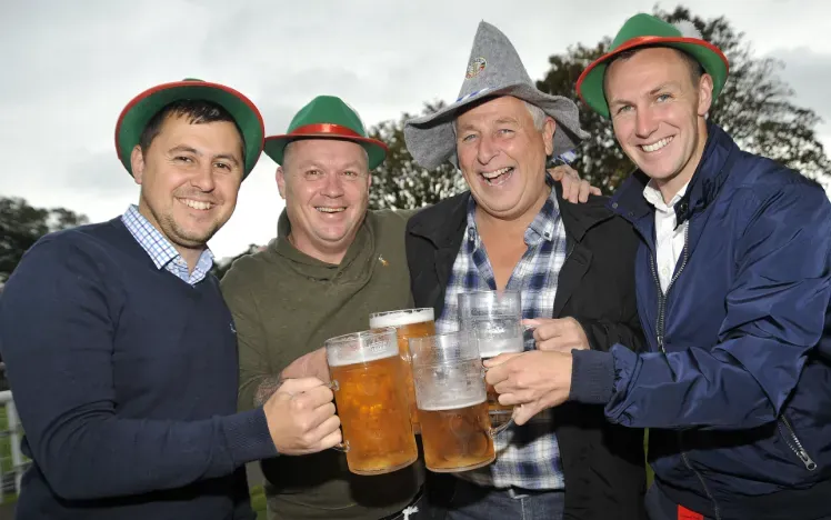 Race goers in hats at Fontwell toast their beer glasses