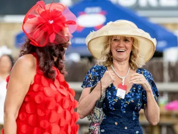 Two ladies smile and laugh as they enter Fontwell Park races
