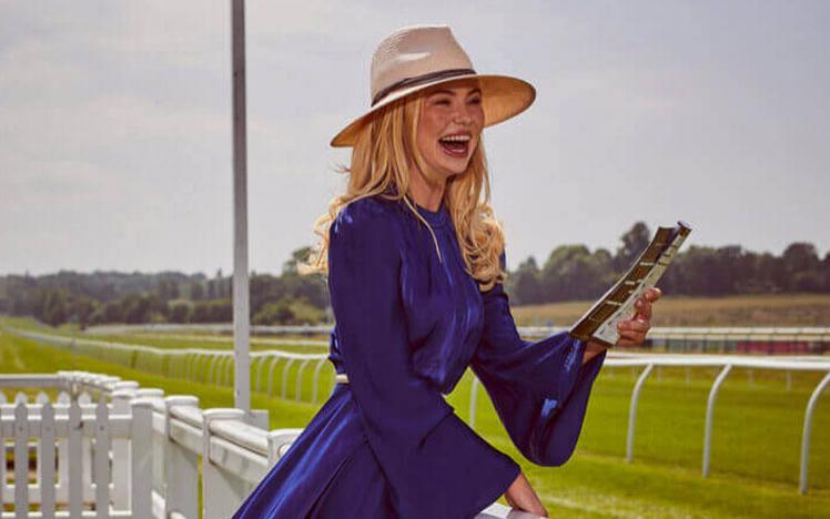  Georgia Toffolo posing for a photo with the track at Fontwell Park Racecourse behind her.