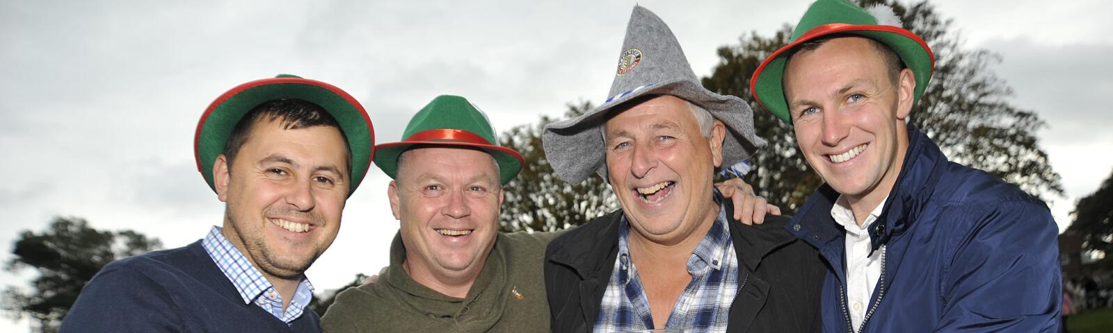 A group of 4 gentlemen toasting their beers and smiling for the camera
