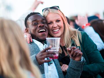 Man and woman enjoy a day at the races with a cold drink in hand