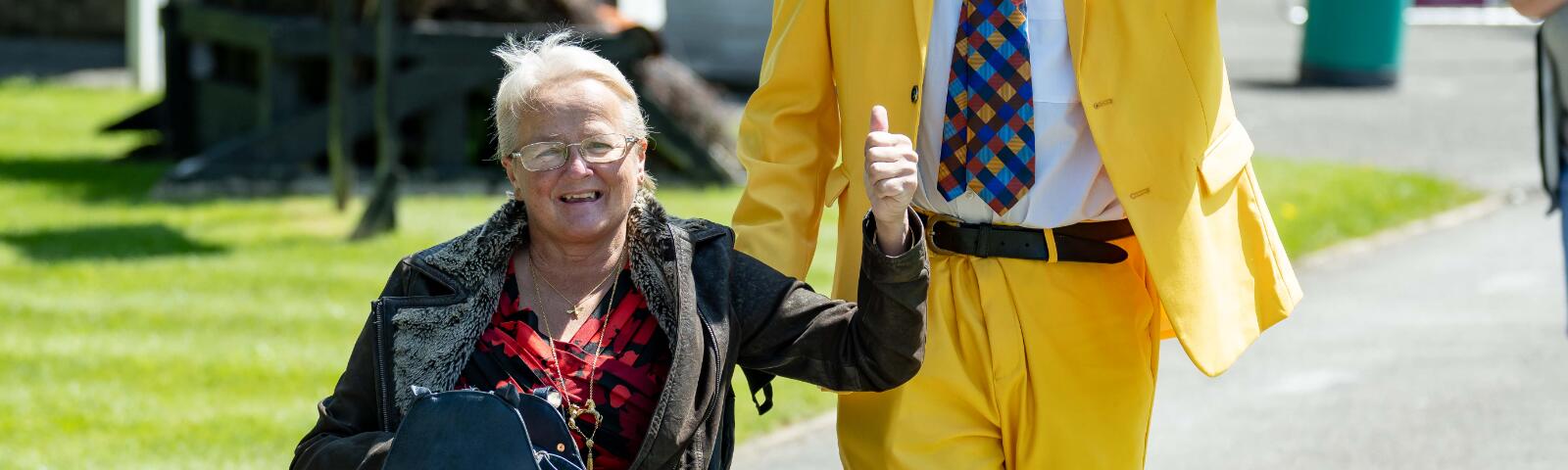 Two visitors to Fontwell - one in a yellow suit, one in a chair, cheer for the camera
